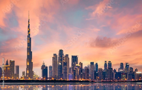 Obraz Stunning panoramic view of the illuminated Dubai skyline during a beautiful sunset. Silky smooth water flowing in the foreground. Dubai, United Arab Emirates.