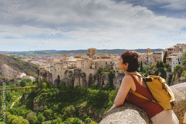 Fototapeta Horizontal view of unrecognizable woman with backpack on holidays looking at the ancient spanish city of Cuenca. Travel and holidays concept in european cities.