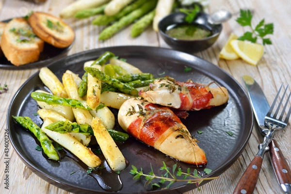 Fototapeta Gebratener weißer und grüner Spargel mit Thymian-Hähnchenfilets im Räucherschinken-Mantel – Fried chicken fillets wrappred with smoked ham and thyme served with roasted white and green asparagus 