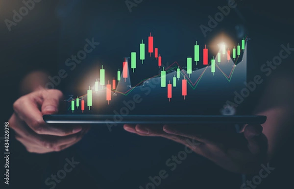 Fototapeta Stock exchange market concept, hand holding digital tablet with graphs analysis candle line on bokeh colors light.