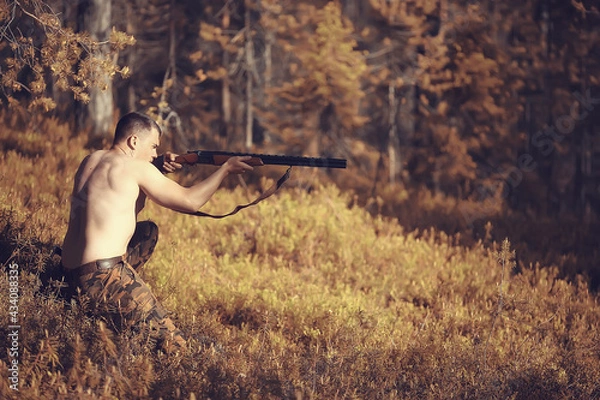 Fototapeta hunting man / hunter with a gun hunting in the autumn forest, yellow trees landscape in the taiga