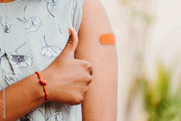 Obraz Indian teen giving thumbs up after getting vaccinated and showing bandage on her arm