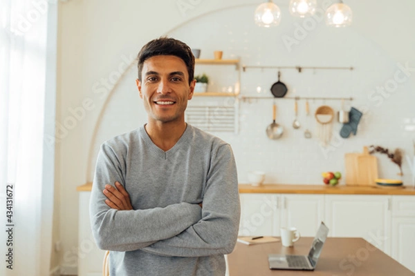 Obraz Portrait of smart smiling Caucasian man standing with arms folded at home posing for photos with copy space. Attractive middle age female freelancer looking at camera