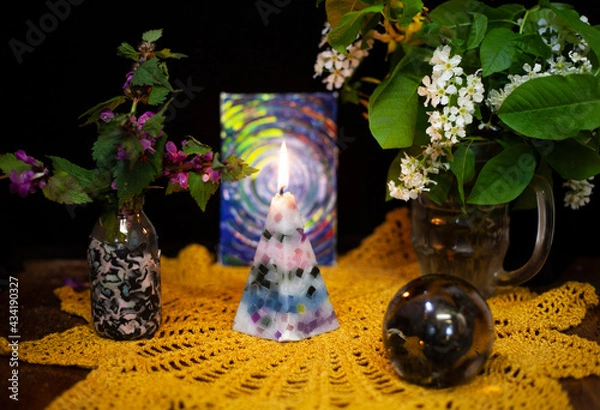 Obraz Still life with a burning candle, a vase with white flowers, purple conditions and a glass ball