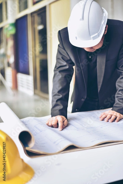 Fototapeta Image of engineer checking blue print.Young architect man or engineer working on his plane project at site construction work