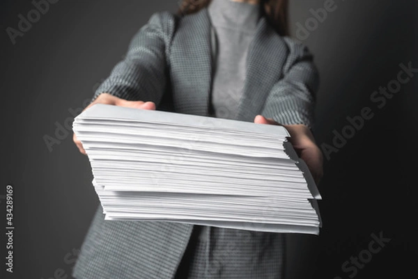 Fototapeta Woman a secretary is showing a heap of documents in her hands.