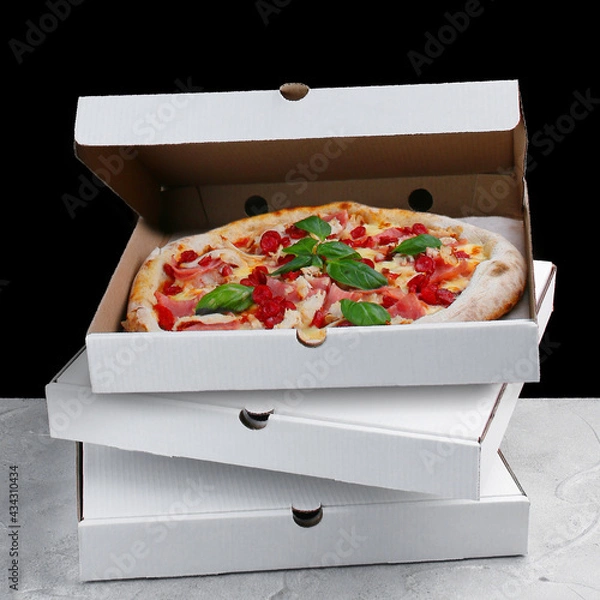 Fototapeta meat pizza inside box. stack of pizza boxes standing on concrete table and black background