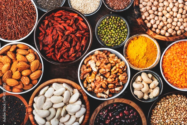 Fototapeta Superfoods, legumes, cereals, nuts, seeds set in bowls on wooden background. Superfood as chia, spirulina, beans, goji berries, quinoa, turmeric and other. Top view