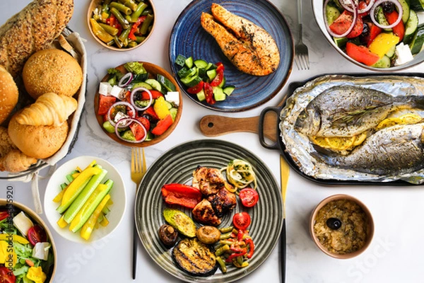 Obraz Lots of healthy food top view.Proper nutrition.Table with food on plates, top view. Healthy food plates top view.Assorted buffet.Healthy dinner.Salmon steak with salad, grilled vegetables and meat on 