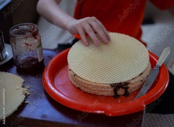 Obraz The boy prepares a sweet cake smears waffles with chocolate and jam
