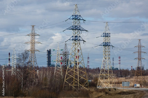 Fototapeta Electricity pylons against the constructions of oil refinery in the early  spring. High voltage power line supports or posts. Transmission towers of electric power lines in Yaroslavl region, Russia