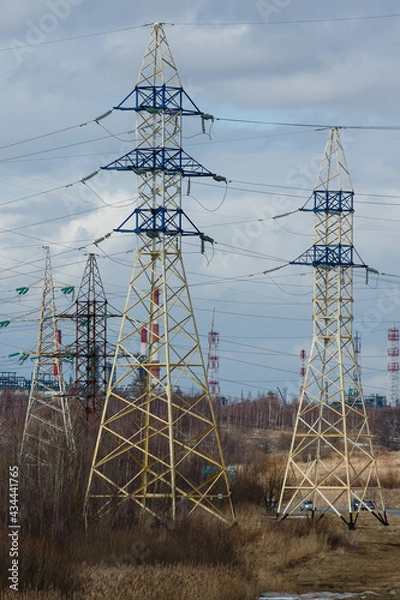 Fototapeta Electricity pylons against the constructions of oil refinery in the early  spring. High voltage power line supports or posts. Transmission towers of electric power lines in Yaroslavl region, Russia