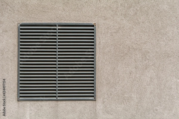 Fototapeta Metal ventilation outlet on a house wall with air slits. Wall background with copy space for text