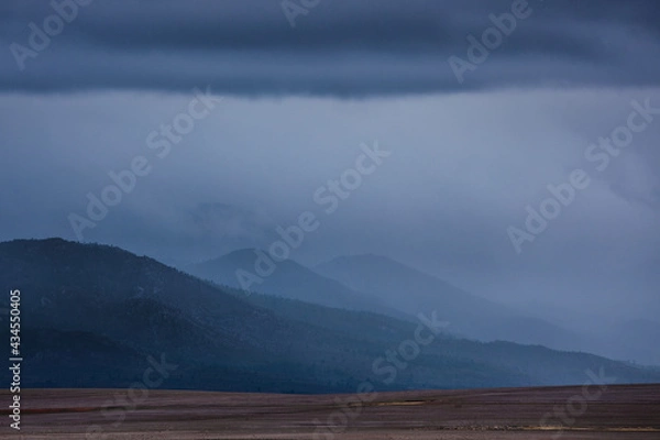 Fototapeta Distant mountains covered in mist and clouds