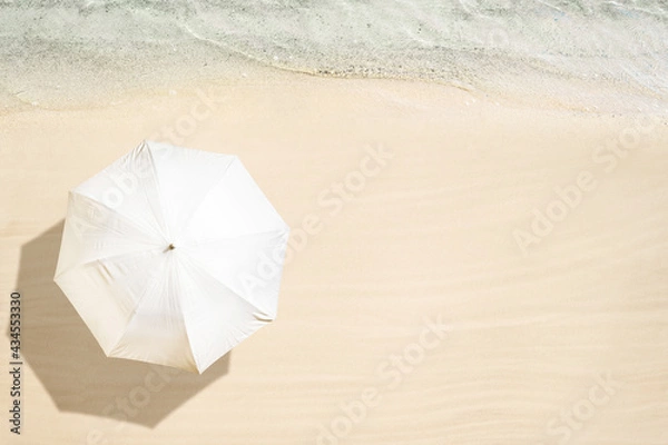 Fototapeta White umbrella on tropical sand beach. Top and aerial view. Ocean coastline. Drone photo. Background