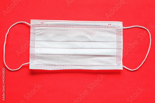 Fototapeta Coronavirus. Protective medical face mask on a red background