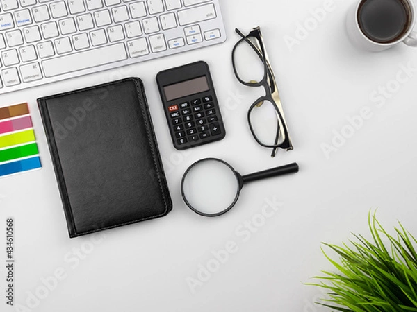 Fototapeta Office place in the workplace. Top view of white office desktop with keyboard, coffee mug and office flower. Copy space for your text. Business, growth and modern work concept