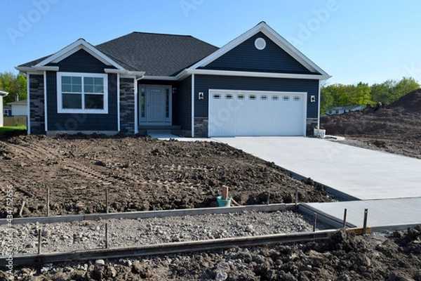 Fototapeta New Home Sidewalk and Driveway Construction with a Concrete Cement Foundation by Builders for a Smooth Surface