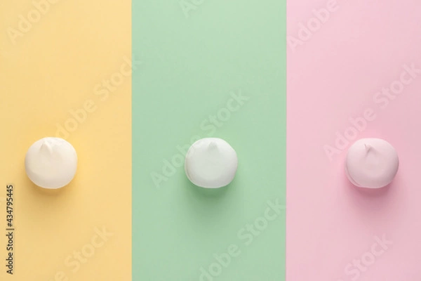 Fototapeta Colorful marshmallows on three different colors backgrounds (yellow, green, pink). Top view, flat lay, copy space. Trendy multi color round zephyr (zephir).