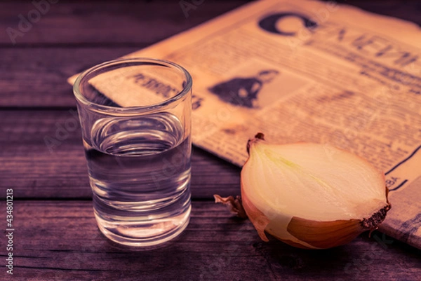 Obraz Shot of vodka with  newspaper and onion on an old wooden table. Close up view