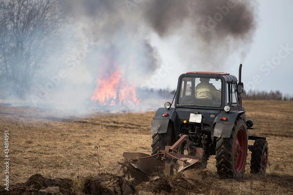 Fototapeta a band of fire in the field. the fire brigade extinguishes the fire with water from the fire hose. fighting with the raging fire element. natural disaster due to forest fires