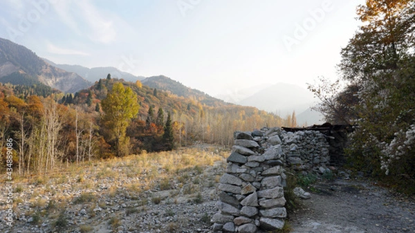 Fototapeta Stone castle, near the walls and inside. Huge stone walls of the fortress. Layer of cement and sand. There are tools for construction. View of the forest, mountains from the fortress. Small window.