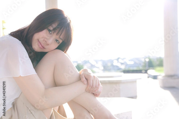 Obraz 座りながら微笑む若い女性