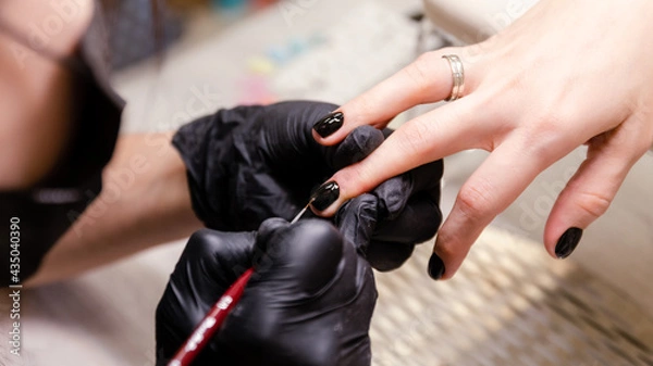 Obraz the manicure master is in the process of working. Hands in black gloves with a brush, close-up