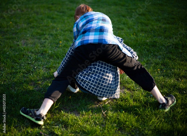 Obraz Boy and girl teenagers are fighting on the grass in nature