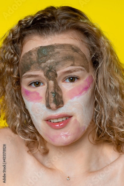 Fototapeta A girl with a wide smile and curly hair, sincerely looks straight