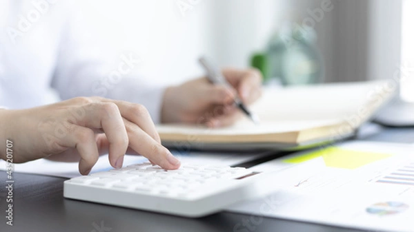 Fototapeta Head of accounting is recording the company's financial growth statistics using graphs as a reference for reviewing and analyzing the results, Taking notes and analyzing data graphs in office.