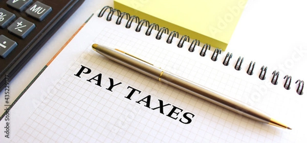 Fototapeta Notepad with text PAY TAXES, next to it lies a calculator. Business concept.