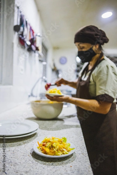 Obraz Vertical shot of a Hispanic woman holding a plate of salad