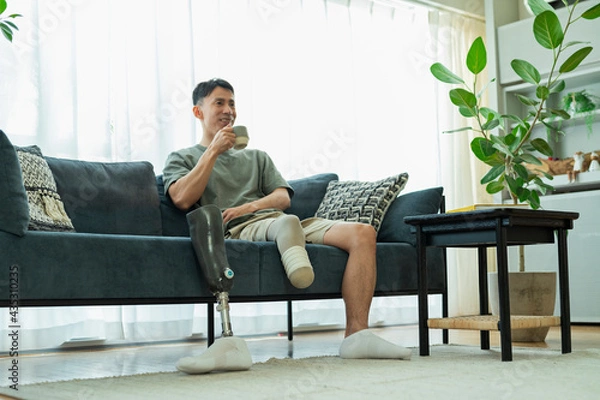Fototapeta ソファでコーヒーを飲む義足の男性
