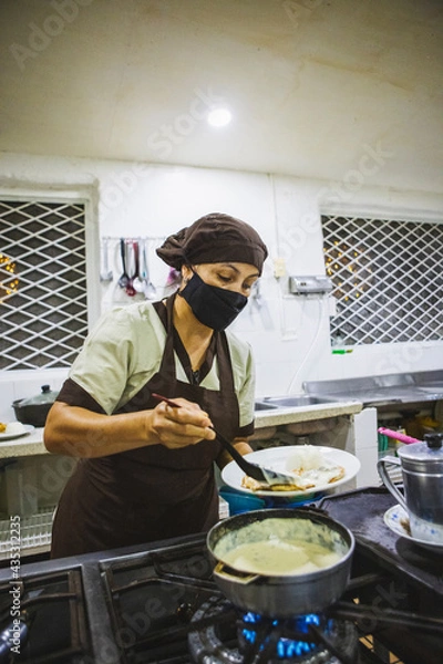 Obraz Vertical shot of a Hispanic woman cooking chicken with mushroom sauce