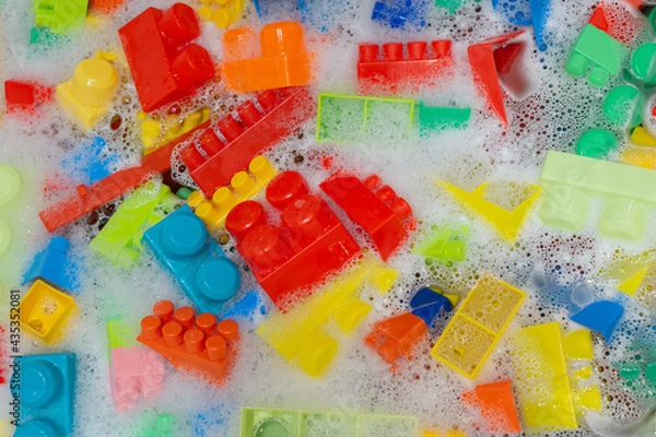 Obraz cleaning colorful toy building blocks. toys hygiene. washing plastic toys in bath with foam