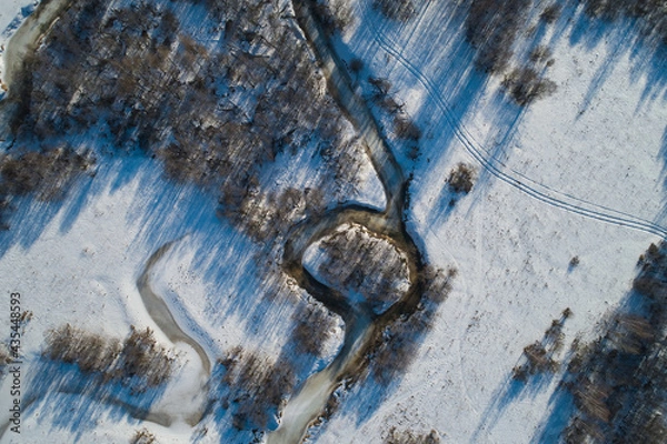 Fototapeta Beautiful Sunny landscape with forest, snow and frozen river. Aerial photography from a drone