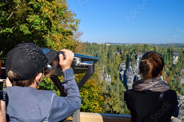 Fototapeta Children look through binoculars into the distance at the rocks and forest in the reserve