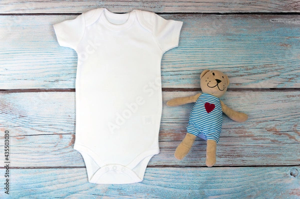 Fototapeta White baby bodysuit mockup with toy on wooden background. Styled stock photography. Mock up