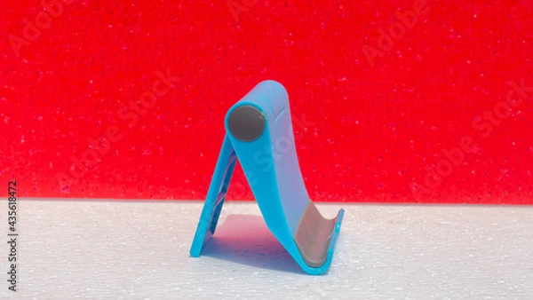 Fototapeta smartphone holder in blue. with a red and white background. very good for business, buying and selling, as well as promotion of product holders.
