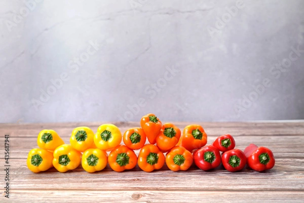 Fototapeta Front view of colorful orange, red and yellow peppers stacked by color.
