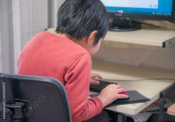 Fototapeta パソコンで作業する小学生の子供。猫背。在宅学習