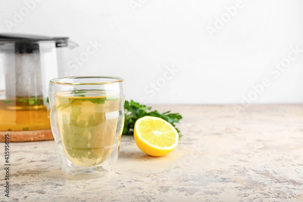 Fototapeta Teapot and cup of hot tea, parsley with lemon on light background