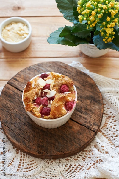 Fototapeta Bread pudding with raspberry. Side view, wooden background.