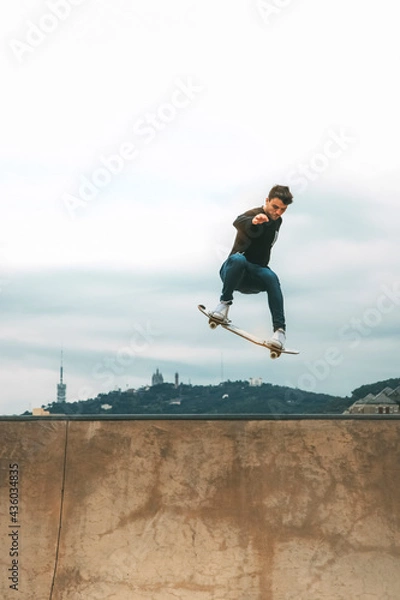 Fototapeta skater jumping high in the air with a snakeboard in a skatepark with white sky in the background with copyspace