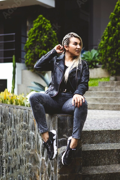 Obraz Vertical shot of a blonde Hispanic female sitting in a park