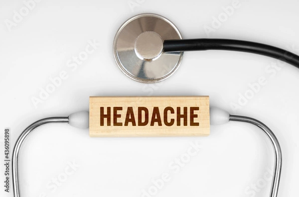 Fototapeta On the table is a stethoscope and a wooden plate with the inscription - HEADACHE