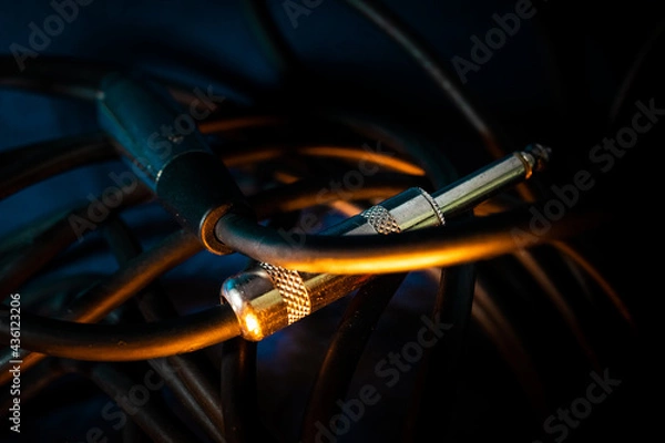 Fototapeta Macro Closeup of Metal Quarter Inch Connector End of Microphone Cable Connector in Cord on Teal Backdrop with Orange Lighting