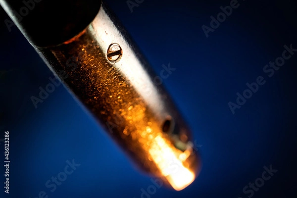 Fototapeta Macro Closeup of Screw on Worn Out and Scratched Male XLR Connector Isolated on Blue Background with Orange Lighting