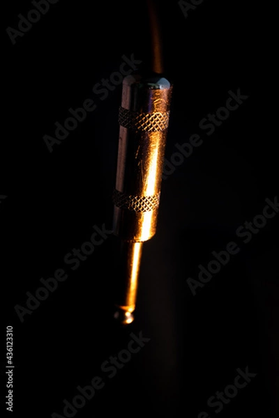 Fototapeta Macro Closeup of Vertical Worn Out Metal Quarter Inch Phone Jack Isolated on Black Background with Orange Lighting